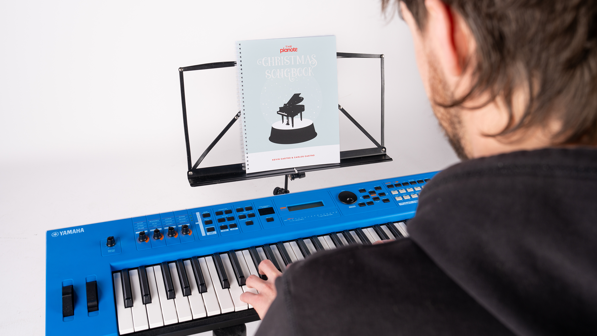 Person playing a blue keyboard with a music stand displaying sheet music in front